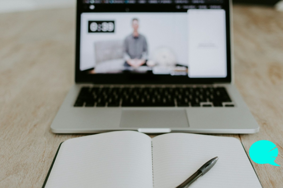 Portátil con una clase de inglés online por videollamada y un cuaderno